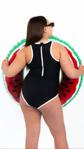 Midnight Current Teen Tween Girls one-piece Swimsuit Swimwear with high neckline, back zipper, removable inserts and age-appropriate cover. Full coverage bum. Black and white, sporty and active design. Girl holding a watermelon inflatable.