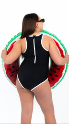 Midnight Current Teen Tween Girls one-piece Swimsuit Swimwear with high neckline, back zipper, removable inserts and age-appropriate cover. Full coverage bum. Black and white, sporty and active design. Girl holding a watermelon inflatable.