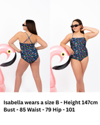 Front and back view of girl wearing the Coastal Bloom floral one-piece swimsuit with side ruching detail, adjustable cross-back straps, and full coverage fit.