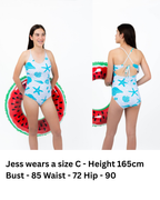 Front and back view of girl wearing the Seafoam Sweetie one-piece swimsuit with seashell and starfish print, adjustable tie-back straps, and full coverage fit.